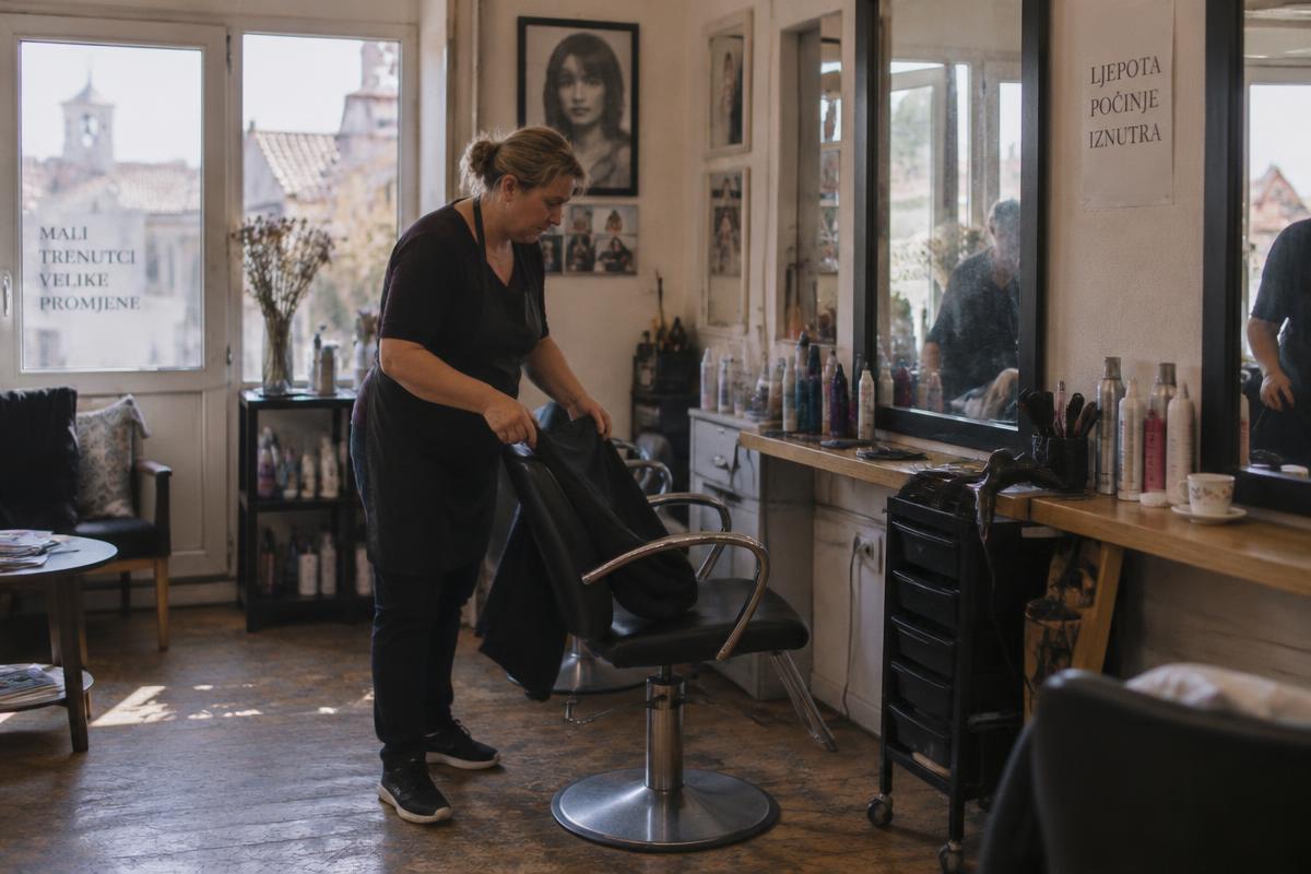 Frizerka uređuje radno mjesto u malom salonu u hrvatskom gradu